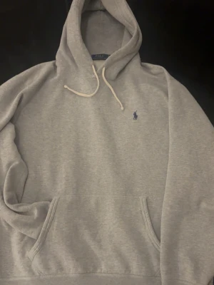 Grå hoodie från Polo Ralph Lauren - Grå Polo Ralph Lauren hoodie i mjukt och skönt material. Enkel och clean med broderad Polo-logga på bröstet, huva med snören och magficka. Perfekt till vardags och lätt att slänga på till typ jeans eller andra chill outfits.  Tar gärna bud 💸 Skriv om du undrar något 📩✨