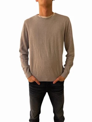 Ljusgrå basic tröja i bomull - En stilren ljusgrå tröja med rund halsringning och långa ärmar. Tröjan har ribbade muddar vid ärmslut och nederkant, vilket ger en enkel och clean look. Perfekt att matcha med jeans för en avslappnad stil.