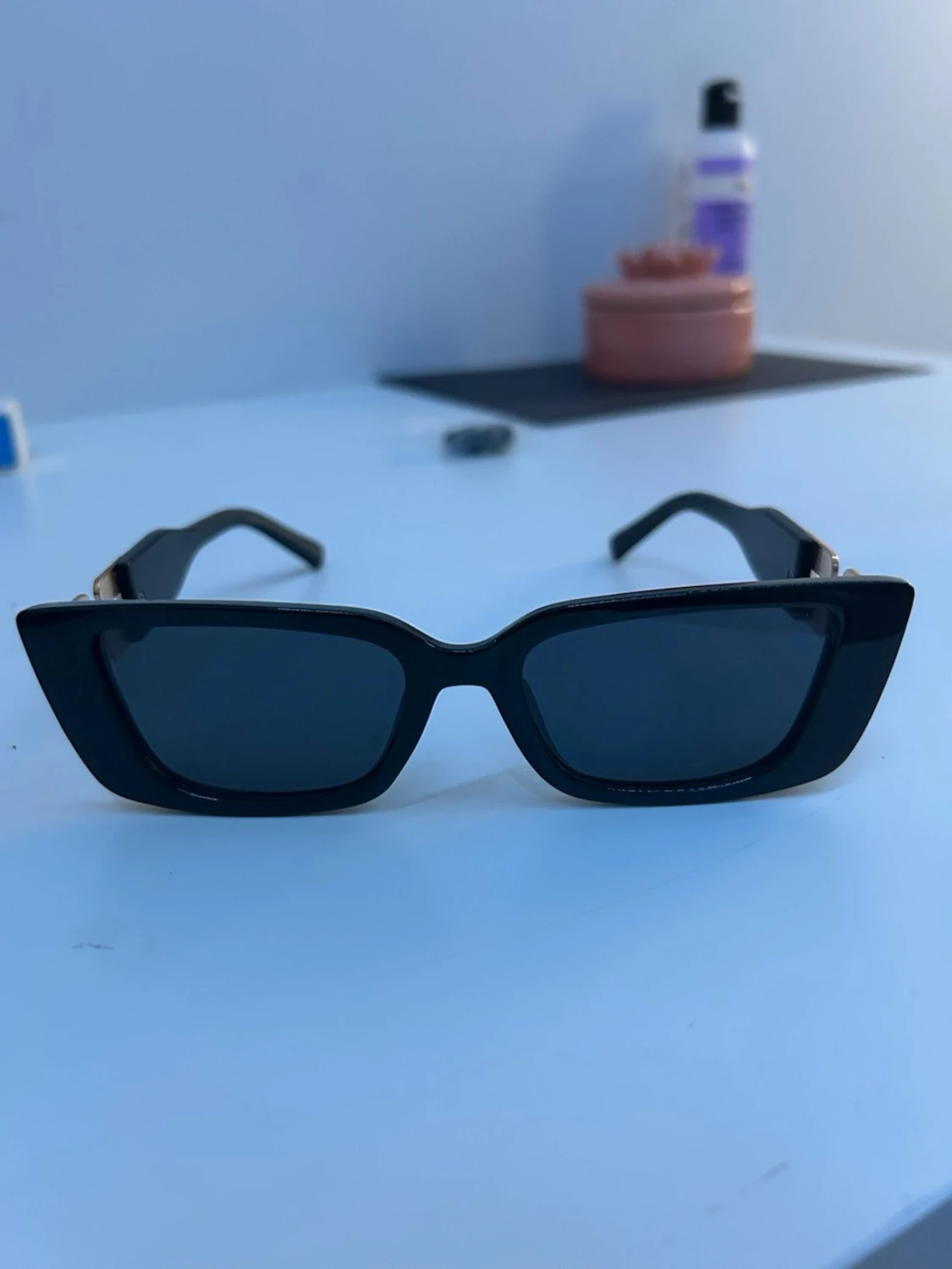 Svarta kantiga solglasögon med gulddetalj