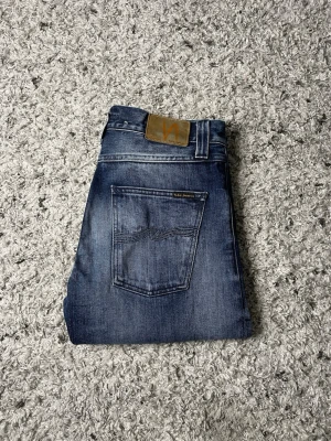 Blå jeans från Nudie Jeans - Säljer ett par nudie jeans med en sjuk wash. Jeansen har en straight fit skulle jag säga och storleken är 31/30! Säljer jeansen för 599kr, ifall ni har några funderingar är det bara att höra av er! (Defekt på bild 5)