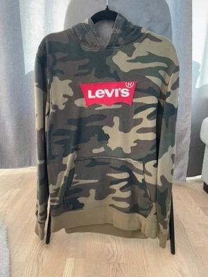 Levi’s tröja  - Levi’s tjock tröja med ficka på midjan.  Färg: Grön camouflage mönster.  Storlek: S  Tröjan är i bra skick men använd.
