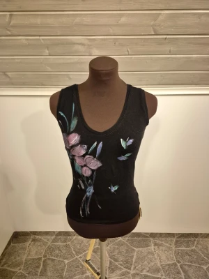 Blommigt linne - Snyggt svart linne med handmålat blommotiv🌺🪻🪷 Köp på en hantvärksmarknad och i fint skick. Det är bara att skriva om man har frågor!😊💖