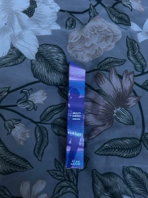 Kiko Milano Beauty Energy Mascara - Säljer en Kiko Milano Beauty Energy Mascara i en snygg lila och blå förpackning med futuristiskt mönster. Mascara ger volym och definition till fransarna och kommer i en smidig tub på 8 ml. Perfekt för dig som vill ha intensiva och markerade ögonfransar.