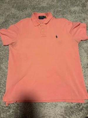 2x piker från Polo Ralph Lauren - Klassiska svart och rosa pikétröjor från  Polo Ralph Lauren med broderad logga på bröstet. Tröjorna har korta ärmar, krage och två knappar vid halsen. Perfekt för en avslappnad men ändå stilren look. Båda i storlek M 