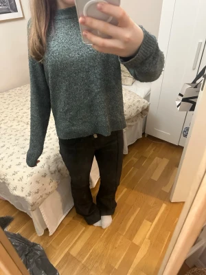 Mörkgrön stickad tröja - Mysig mörkgrön stickad tröja med rak passform och långa ärmar. Tröjan har en enkel, klassisk design utan synliga loggor eller mönster och är tillverkad i ett mjukt, melerat garn som ger en avslappnad look.