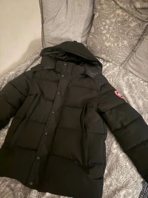  Canada Goose wyndham - Säljer en svart pufferjacka från Canada Goose med huva och klassisk logga på ärmen. Jackan har dragkedja och knappar framtill, stora fickor och en riktigt fluffig look. Perfekt för kalla dagar och riktigt snygg till alla outfits. Kan bytas emot loubs Ralph lauren puffer jacka fraktar samma dag passar M pälsen finns det är en parka den ska vara stor