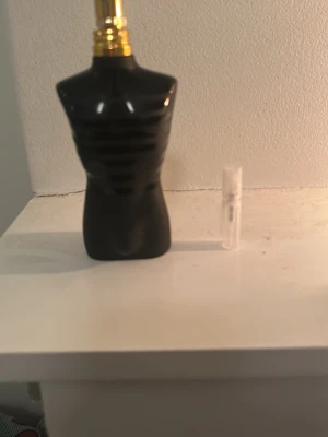 Svart parfym Jean Paul Gaultier Le Male - Säljer en ikonisk parfym från Jean Paul Gaultier, Le Male, i svart flaskdesign formad som en manlig torso med gulddetaljer. Flaskan är tillverkad i glas och har en unik, stilren look som sticker ut i badrumshyllan.