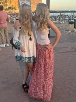 Röd paisleymönstrad långkjol - Säljer en röd långkjol med paisleyinspirerat mönster i vitt. Kjolen har en avslappnad passform och är gjord i ett lätt och luftigt material, perfekt för varma dagar. Midjan är elastisk för extra komfort och kjolen har en bohemisk vibe. Tecken på användning