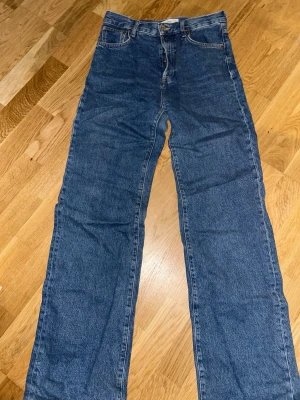 Blå raka jeans från Mango - Klassiska blå jeans med rak passform och femficksdesign. Jeansen har normal midja och är tillverkade i slitstarkt bomullsdenim. Perfekta för en avslappnad och tidlös stil. Lite slitna vid slutet av benen. Kan sänka priset!!