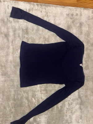 Mörkblå långärmad topp - Mörkblå långärmad topp med bred, rundad urringning och diskret spetskant runt halsen. Tunn och mjuk i materialet, perfekt att styla med jeans eller kjol. Skriv till mig om du vill se hur den sitter på.☺️
