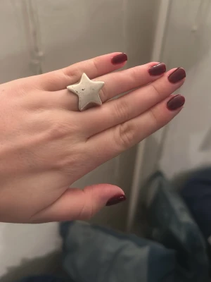 Silvrig ring med stjärnform från l8h - Cool ring i metall med en stor stjärna i silvrig färg. Perfekt statement piece för dig som gillar unika accessoarer och vill sticka ut lite extra. Passar till alla outfits där du vill lägga till en lekfull touch.