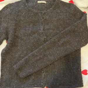 Brun kofta i ull från Gina Tricot - Mysig brun kofta från Gina Tricot i fluffig ullmix. Klassisk rak modell med rund halsringning och knäppning framtill med fyra knappar. Perfekt för lager-på-lager under kyliga dagar.