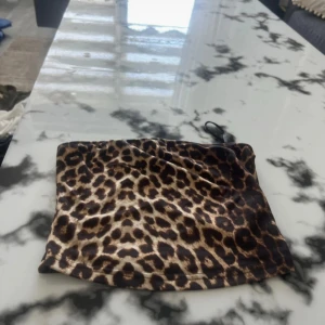 Leopardmönstrad kuvertväska - Säljer en snygg kuvertväska med leopardmönster. Perfekt att ha med sig när du vill sticka ut lite extra. Väskan har en smidig dragkedja upptill och är lätt att bära med sig. Materialet känns mjukt och följsamt.