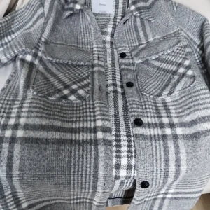 Grå rutig overshirt från Bershka - Säljer en snygg grå och vit rutig overshirt från Bershka. Jackan har stora bröstfickor, svarta knappar och klassisk krage. Perfekt lager-på-lager-plagg med mjukt material och avslappnad passform.