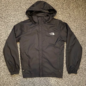 Svart vind/regnjacka från The North Face - Säljer en svart vindjacka från The North Face Summit Series med huva och dragkedja. Jackan har logga på bröstet och ryggen, elastiska muddar och två sidofickor. Perfekt för blåsiga dagar och outdoor-aktiviteter.                     Storleken är L men sitter som S, jag är 183 66kg och den passar mig perfekt 