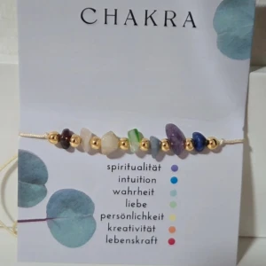 Justerbart Chakra Armband med 7 Ädelstenar - Healing & Wellness - Armbandet är tillverkat med sju olika ädelstenar som symboliserar kroppens sju chakran. Armbandet är justerbart med en smart knut (macramé-stil) som gör att det passar de flesta handleder (upp till 28 cm i omkrets). Det är prytt med små guldfärgade pärlor för extra detalj.  Tema: Chakra, Wellness, Healing, Spiritualitet.  Stenar: Sju olika stenar (enligt traditionen representerar de rot-, sakral-, solar plexus-, hjärt-, hals-, tredje ögat- och kronchakrat). Färg på snöre/metalldetaljer: Guldfärg