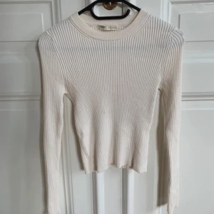 Vit ribbad långärmad tröja Pull&Bear - Säljer en vit ribbad långärmad tröja från Pull&Bear. Tröjan har rund halsringning och är figurnära i modellen. Materialet är mjuk bomull med stretch som gör den skön att bära. Perfekt att styla med jeans eller kjol för en clean look.