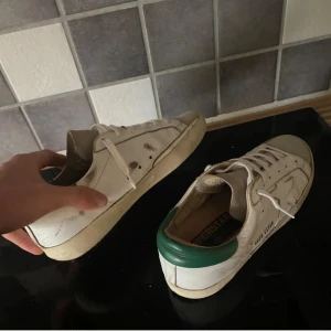 Golden goose Superstar sneakers vit/grön - Säljer ett par riktigt feta golden goose superstar med grön häl och mocka framtill. Synligt använda men skorna har en sliten stil som gör att de ser ut som design. Storlek 41. Skriv vid frågor!! Pris är diskuterbart!!