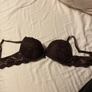 Brun spets-bh från Cubus A70 - Säljer en brun push up-bh från Cubus i storlek A70.Använt en gång! Bh:n har vacker spets med blommigt mönster, vadderade kupor och en liten rosett med smycke framtill. Axelbanden är justerbara och materialet är mjuk polyester.Ordenarie pris 250. Säljer för 200kr. Priset är inte hugget i sten, utan går att pruta!