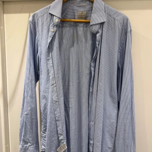 Blåvit randig skjorta La Chemise - Snygg blå och vit randig skjorta från La Chemise Norrmalm med extra långa ärmar. Klassisk krage, knäppning framtill och tunn bomullskvalitet som känns fräsch och stilren. Perfekt för dig som gillar en clean look med lite edge. Strl 42/ L extra long arm 