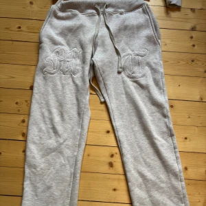 Grå mjukisbyxor med brodyr - Snygga grå mjukisbyxor med broderade bokstäver på framsidan och dragsko i midjan. Perfekta för chill dagar eller när du vill vara bekväm men ändå se cool ut. Mjukt material och avslappnad passform.