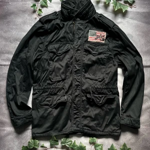 Vintage Ralph Lauren Polo Jeans Co. “Flag Field Jacket” - 🎨 Färg: Svart 📏 Storlek: M (normal passform) 📐 Mått: (kan fyllas i om du mäter) ♻️ Skick: Mycket bra vintage-skick – lättare bruksspår men inga defekter 🧵 Material: Bomull & nylon  ‼️ Skickas dagen efter köpet genomförs! ‼️