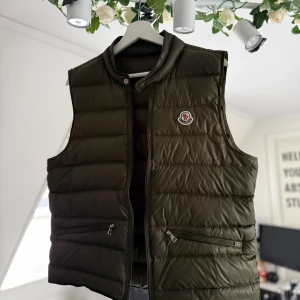 Olivgrön Moncler Gui väst - Tjena säljer nu en, mycket fin Moncler Gui väst, den är använd i ca ett halvår, storlek 2/M, dragkedjan kan vara lite klurig ibland men inget större problem, har du någon fundering är de bara till att höra av sig, ge även gärna prisförslag!