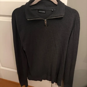 Mörkgrå half zip-tröja Jack & Jones - Mörkgrå långärmad tröja från Jack & Jones med snygg half zip-dragkedja i halsen. Tröjan har en klassisk, lite högre krage och är tillverkad i stickat material som passar perfekt till allt. Enkel och stilren design som funkar till det mesta. Köpt för 500kr och är nästan alldrig använd