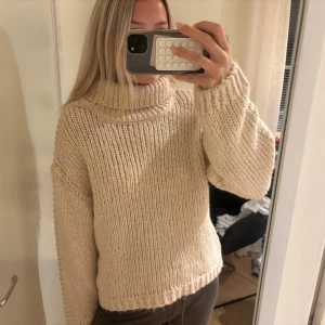 Beige stickad polotröja Gina Tricot - Säljer en chunky beige stickad polotröja från Gina Tricot med bred krage och långa ärmar. Tröjan har loose passform och coola guldfärgade detaljer längs ärmen. Perfekt för dig som gillar mysiga och trendiga plagg med lite extra edge, aldrig använd