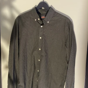 Grön skjorta från Morris - Snygg grön skjorta  från morris, vita knappar och broderad logga på bröstet. Skjortan är långärmad och har en stilren passform som funkar till många looks. Materialet är mjukt bomull