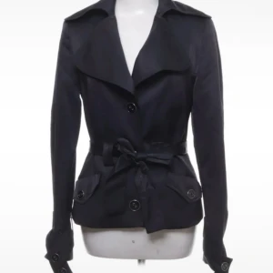 Intressekoll trenchcoat  - Intressekoll!!! Snygg trenchcoat med klassisk krage och knytbälte i midjan. Jackan har stora knappar framtill, fickor med lock och långa ärmar med knappar vid ärmslut.
