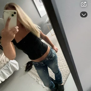 Blå bootcut jeans låg midja - Säljer ett par blå jeans med bootcut och låg midja. Jeansen har slitna detaljer och är från märket GUESS. Snygg tvätt med lite ljusare partier och lätt urtvättad look. Det har lagats två hål mellan benen på byxorna men inget man lägger märket till