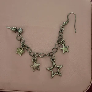 Silverfärgat örhänge med stjärnor - Coolt örhänge i silverfärg med flera hängande stjärnberlocker i olika storlekar. 