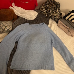 Ljusblå stickad tröja från Vero Moda - Mysig ljusblå stickad tröja från Vero Moda i storlek M. Tröjan har en enkel design med ribbade muddar vid hals, ärmslut och nederkant. Perfekt för dig som gillar en chill och clean look med långärmad passform.