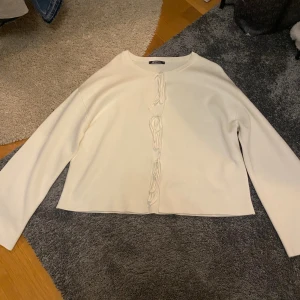 Vit kofta med snörning från Gina Tricot - Säljer en vit kofta från Gina Tricot med snygg snörning framtill. Koftan har långärmade, lite vidare ärmar och är gjord i mjukt material som känns skönt mot huden. Perfekt för dig som gillar minimalistisk stil med en twist. Pris går att diskutera.