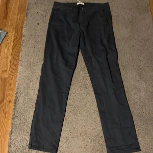 Svarta chinos från MNG, storlek 164 - Svarta chinos från MNG i storlek 164. Klassisk rak passform med bälteshällor, knapp och dragkedja framtill samt fickor både fram och bak. Snygga och stilrena byxor i bomull som passar perfekt till en clean och enkel look.