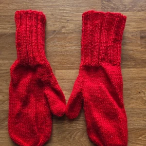 Röda stickade tumvantar - Säljer ett par röda stickade tumvantar med lång, ribbad mudd. Vantarna är i ett mjukt och varmt garn, perfekta för kalla dagar. Färgen är intensivt röd och designen är klassisk utan mönster eller detaljer. Grymma för dig som vill ha något enkelt och snyggt.