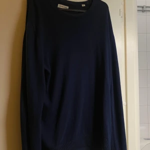 Marinblå stickad tröja Jack & Jones - Snygg marinblå stickad tröja från Jack & Jones med rund hals och långa ärmar. Perfekt för dig som gillar enkel och stilren design. Tröjan har ribbade muddar vid ärmslut och nederkant för extra komfort.