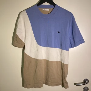 Blå och beige t-shirt från Zara sparsamt använd medium  - Snygg t-shirt från Zara med coola färgblock i ljusblått, beige och vitt. T-shirten har rund hals, korta ärmar och ett litet broderat motiv på bröstet. Mjuk bomullskvalitet som känns skön mot huden. Perfekt för dig som gillar stilrena och moderna plagg. Medium. Sparsamt använd. 