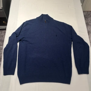 Quarter-Zip från Polo Ralph Lauren - Blå tröja med lång ärm, tillverkad i mjuk ull. Mycket väl ohändertagen, fint skick. Nypris 2595kr. Storlek L.
