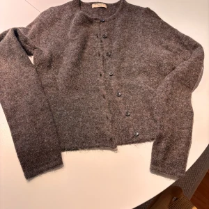 Brun kofta från Gina Tricot XS - Mysig brun kofta från Gina Tricot i storlek XS. Koftan är stickad i ullblandning och har rund hals samt knappar framtill. Perfekt för lager-på-lager och chill dagar. Enkel och stilren design som funkar till många outfits.