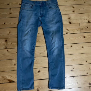 Blå Replay Grover jeans - Säljer ett par blå jeans från Replay modell Grover i klassisk straight fit med fem fickor och normal midja. Jeansen har snygg tvättad look och är tillverkade i mjukt denimtyg. De har en liten slitning vid grenen, men de är bara snyggt. Perfekta för dig som gillar en enkel och stilren vibe. De är även perfekta nu till hösten!🔥