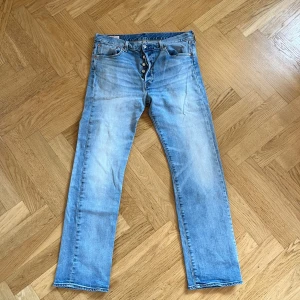Levi's 501 ljusblå jeans straight fit - Klassiska Levi's 501 jeans i ljusblå tvätt med raka ben och knappgylf, dessa jeansen är vintage och är inköpta på 90-talet. Jeansen har fem fickor, nitar i kopparfärg och den ikoniska röda Levi's-taggen bak. Perfekt för dig som gillar en tidlös och avslappnad stil. Storleken är lite oklar då de är så gamla men hör av er vid några frågor