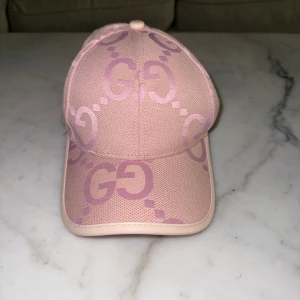 Guccci keps - Säljer en snygg rosa keps från guccci Kepsen har böjd skärm, justerbar rem bak i ljusrosa läder och är tillverkad i ett tåligt tygmaterial. Perfekt accessoar för att lyfta din outfit med lyxig känsla.