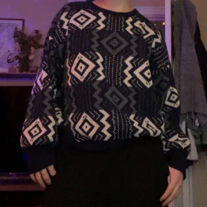 Mönstrad stickad tröja i blått och vitt - Säljer en stickad tröja i storlek M med coolt geometriskt mönster i mörkblått, vitt och grått. Tröjan har rund halsringning och långa ärmar, perfekt för att hålla sig varm under kyliga dagar.