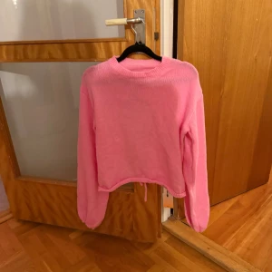 Rosa stickad tröja Forever 21 x SHEIN - Säljer en rosa stickad tröja från Forever 21 x SHEIN i storlek M. Tröjan har långärmade puffärmar, croppad passform och en öppen rygg med rund cut-out och snörning. Perfekt för dig som vill ha en unik och trendig look. Oanvänd med lappen kvar på. 