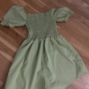 Ljusgrön kort playsuit från SHEIN - Supersöt ljusgrön playsuit från SHEIN i storlek XS. Playsuiten har puffiga korta ärmar, smockad överdel. Perfekt för varma dagar med sin lätta bomullskänsla och trendiga volymärmar.