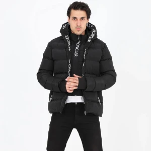 Svart Moncler pufferjacka med huva - Säljer en svart pufferjacka från Moncler med stor huva och tydlig logga på både huva och ärm. Jackan har dragkedjor på fickorna och framtill, samt breda kanaler för en riktigt fet look. Perfekt för dig som vill ha en stilren och varm jacka med streetkänsla.