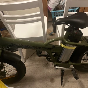 Yosemite Elcykel Fatbike/ Ny lagt batteri - Yosemite elcykel med kraftiga fatbike-däck, batteri och eldriven motor. Cykeln har grönt ram, breda däck för stabilitet och komfort. Viss smuts och mindre slitage syns på ramen och skärmarna, men i övrigt ser cykeln ut att vara i gott skick. Perfekt för både stad och terräng.