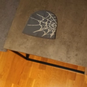 Grå mössa med spindelnätsmönster (y2k) - Cool grå mössa med vitt spindelnätsmönster på sidan, perfekt för dig som gillar unika detaljer. Tillverkad i 100% akryl som är mjukt och skönt mot huvudet. Passar dig som vill sticka ut lite extra med din stil.
